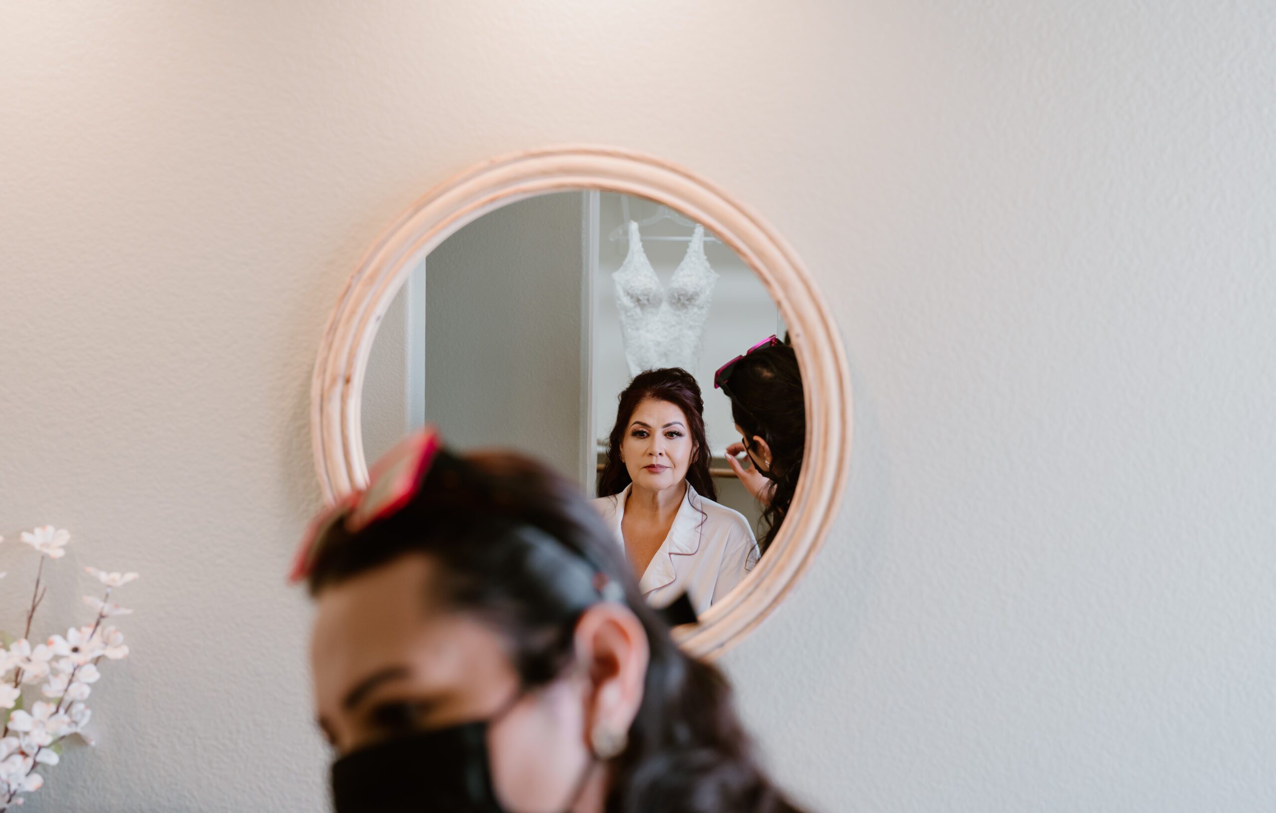 bride looking in the mirror while she gets her hair and makeup done
